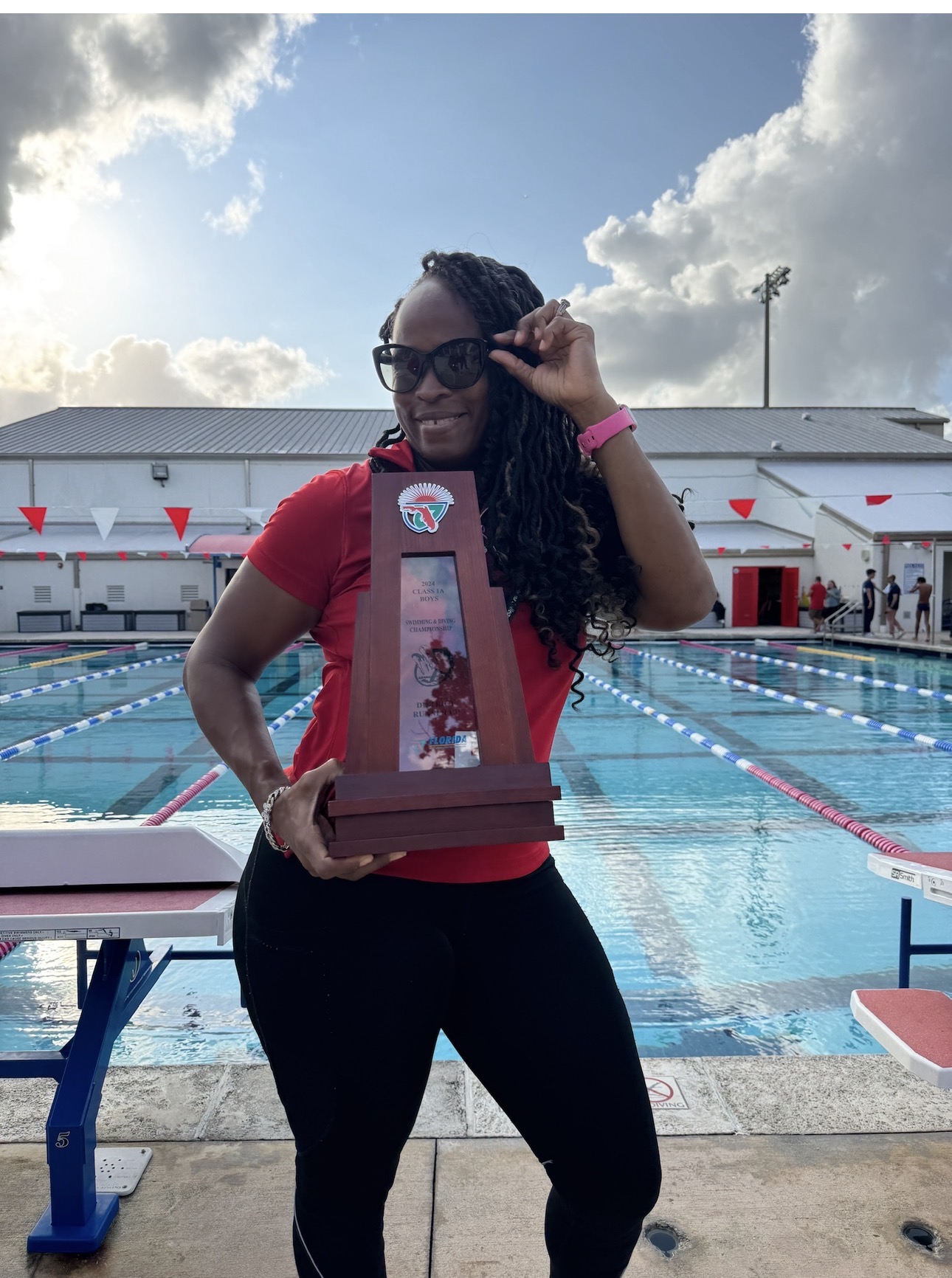 Coach Bobbi Perry holding the 2024 district swimming championship runner-up trophy